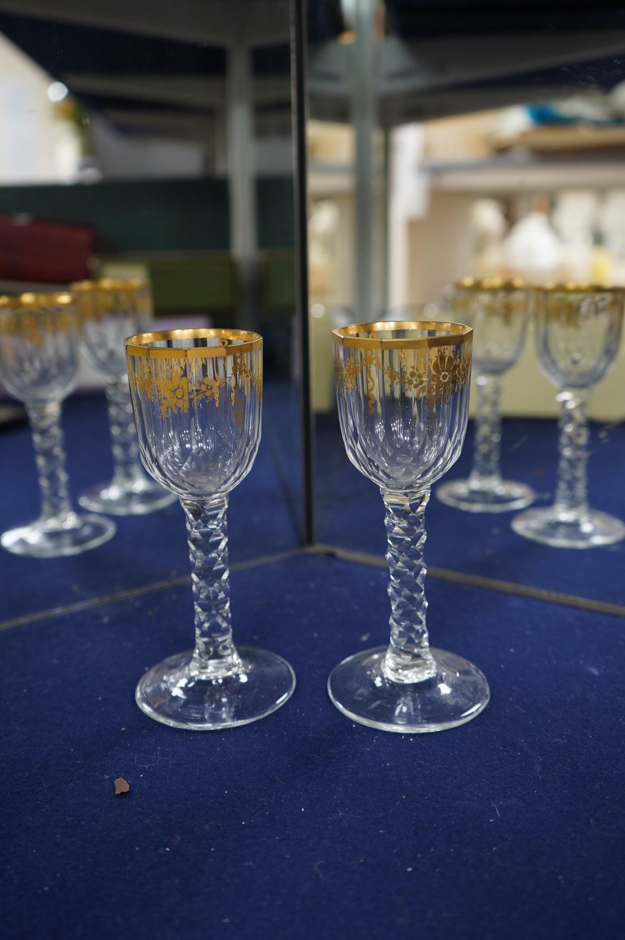 A pair of early 18th century octagonal glasses with gilt floral swagged decoration and facetted stems. Condition - slight wear to gilding otherwise good